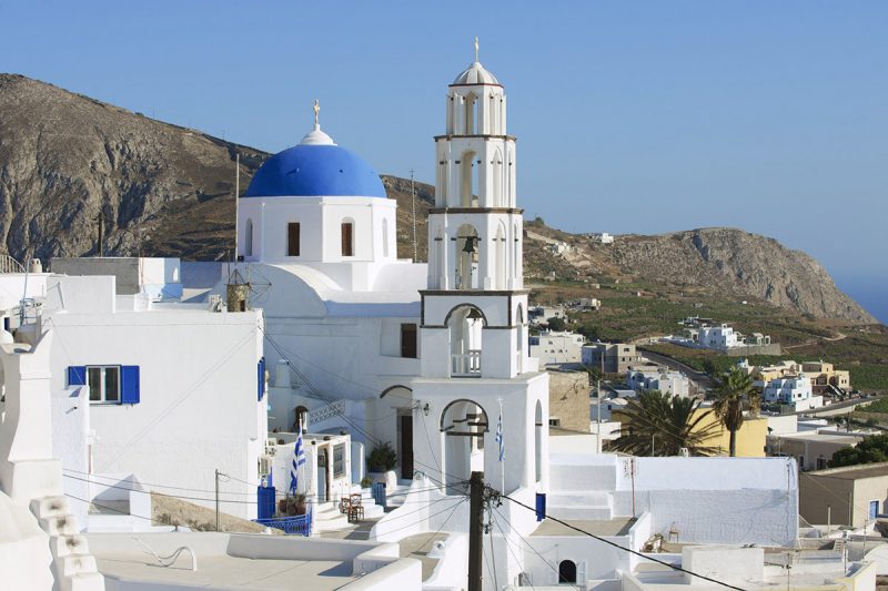 Igreja ortodoxa de cúpula azul e torre sineira na cidade de Pyrgos, Santorini
