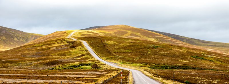 Uma estrada panorâmica no outono no Parque Nacional Cairngorms, Escócia